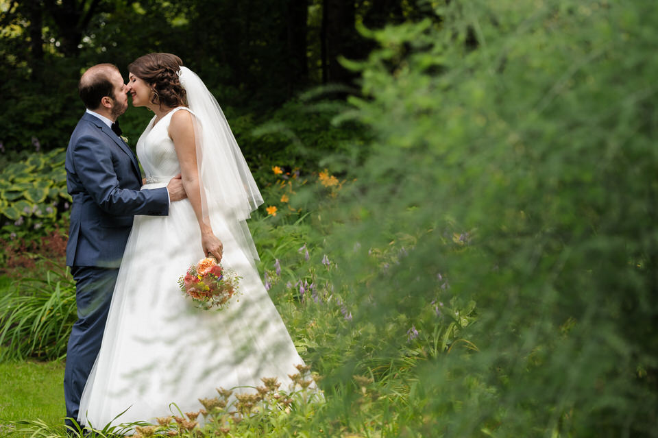 Bride and groom kissing framed by lush greenery