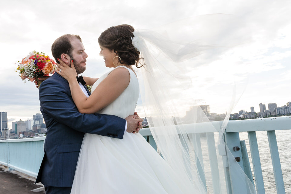 Bride and groom on a bridge with Montreal skyline behind them