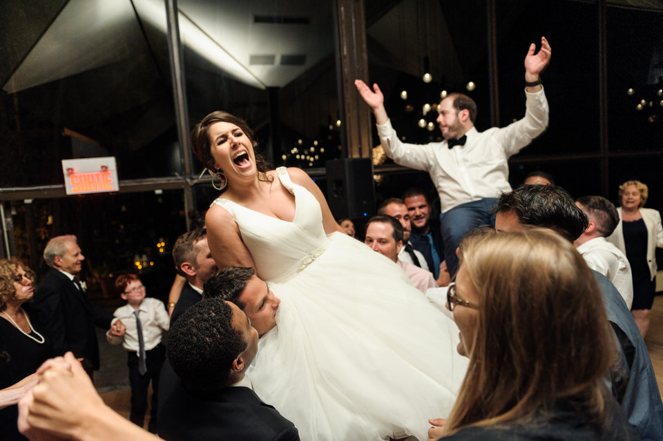 Bride and groom being lifted in chairs