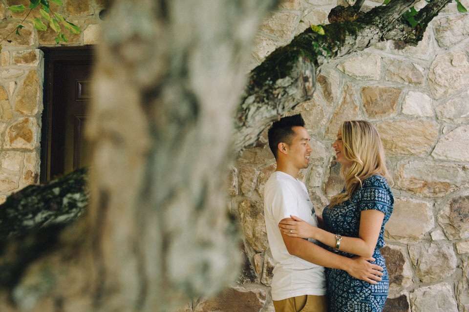 Engaged couple embracing near a stone wall