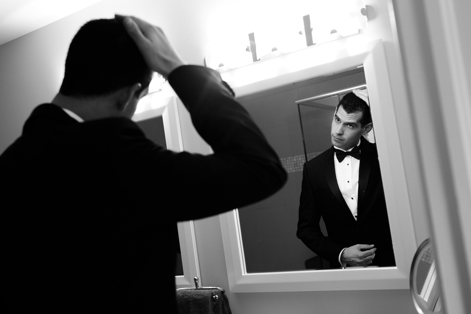 Groom fixing his hair in the mirror