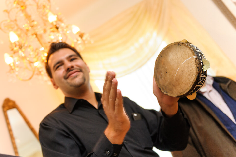 Man playing a small drum to celebrate the bride's arrival