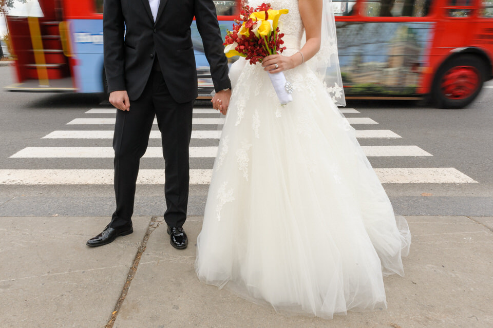 Bride and groom standing in front of a crosswalk with blurry traffic behind
