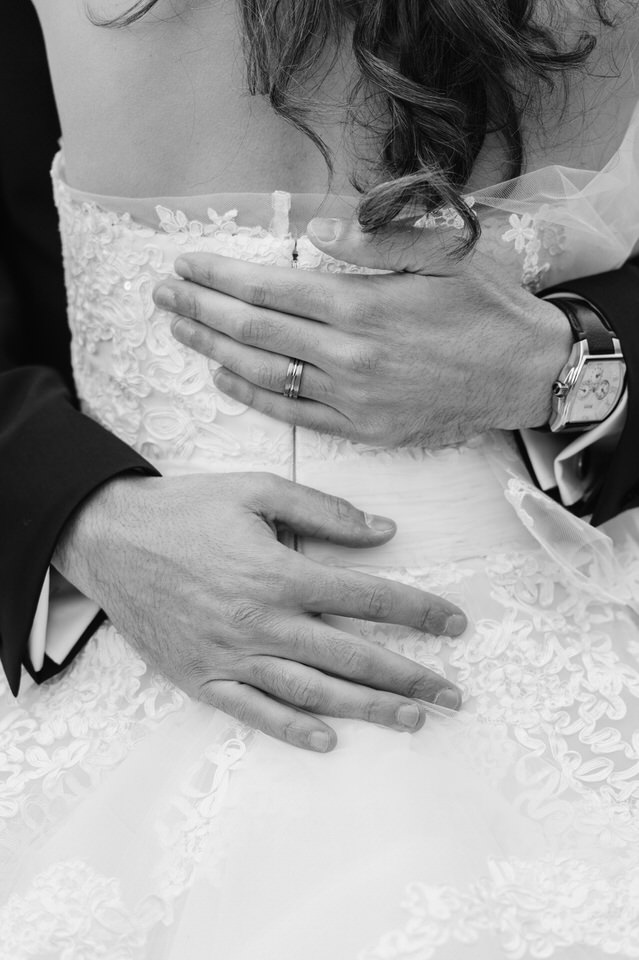 Close up of groom's hands on bride's back