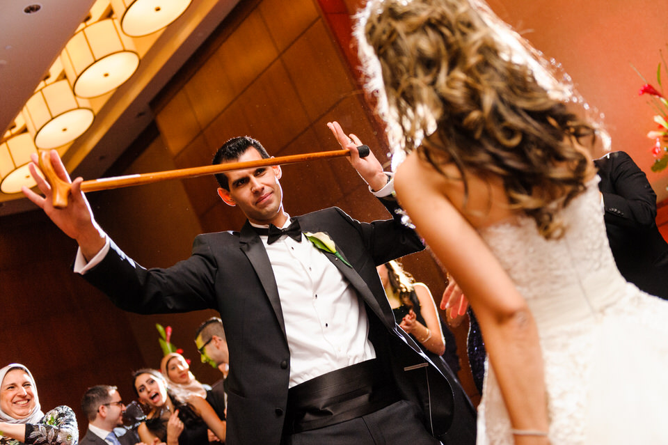 Groom dancing with a walk stick at Arab wedding