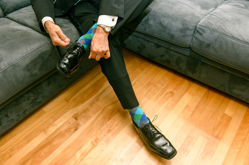 Man tying his shoes with colourful wedding socks