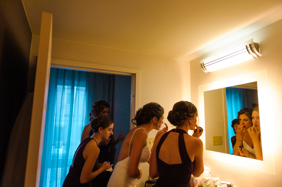 Bridesmaids and bride getting ready in the bathroom of the hotel