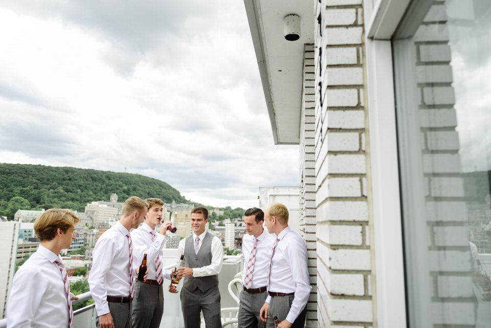 Groomsmen hanging out on the balcony with beers before wedding