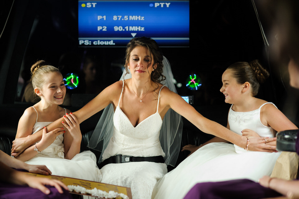 Bride holding her flower girls safely in the limo with no seat belts