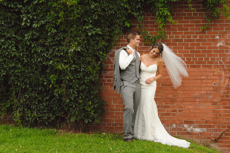 Bride and groom laughing as her veil blows in the wind