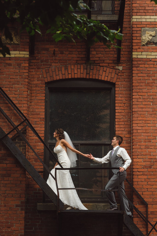 Wedding couple climbing fire escape at Chateau Saint-Ambroise