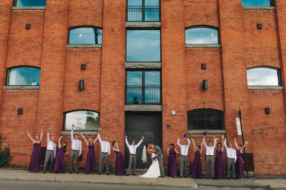The entire wedding party standing in front of a tall building and cheering