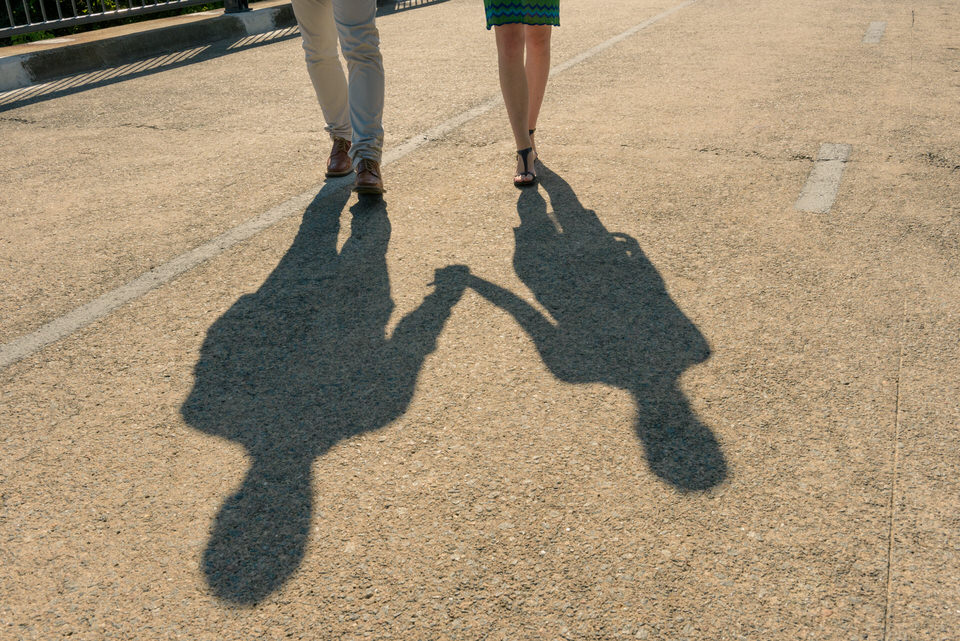 Ombre d'un couple se tenant par la main se reflète sur le bitume