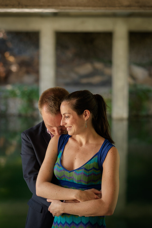 Fiancé tenant sa fiancée dans ses bras et embrassant son épaule près d'un ruisseau au parc Jean Drapeau