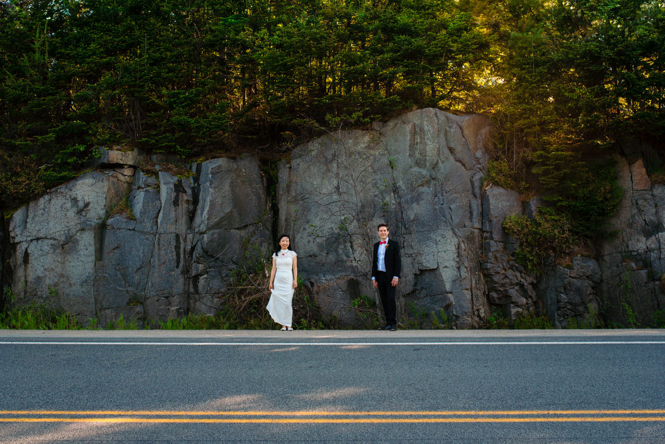 Wedding portrait in front of a craggy rock face near a country highway
