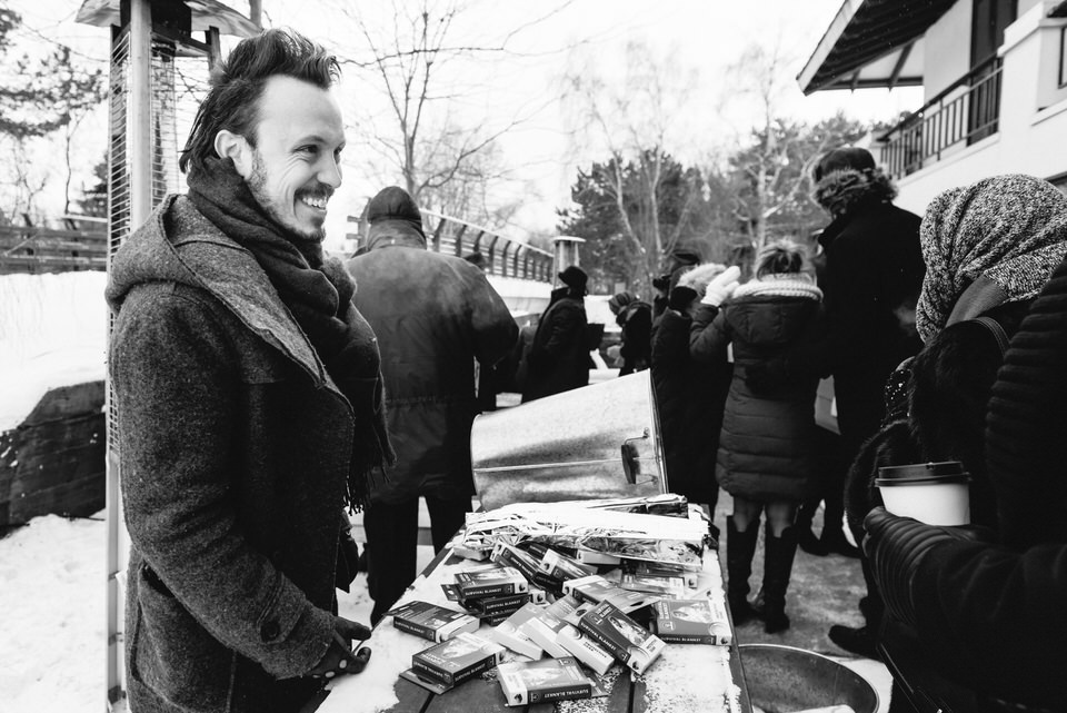 Man smiling and greeting guests at winter wedding