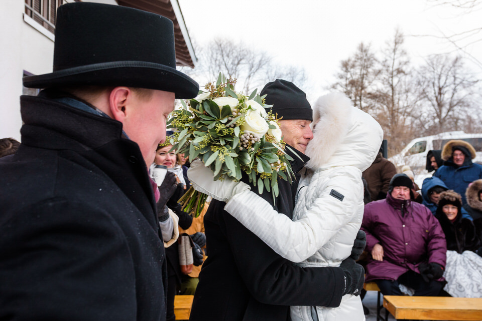 Bride hugging her father as her fiancé watches