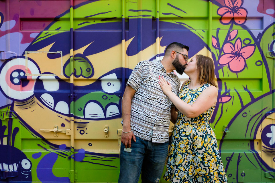 Engaged couple in front of graffiti in park