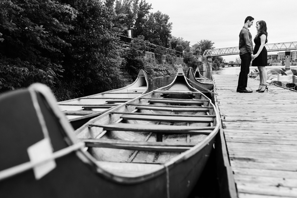 Engaged couple on a dock near canoes