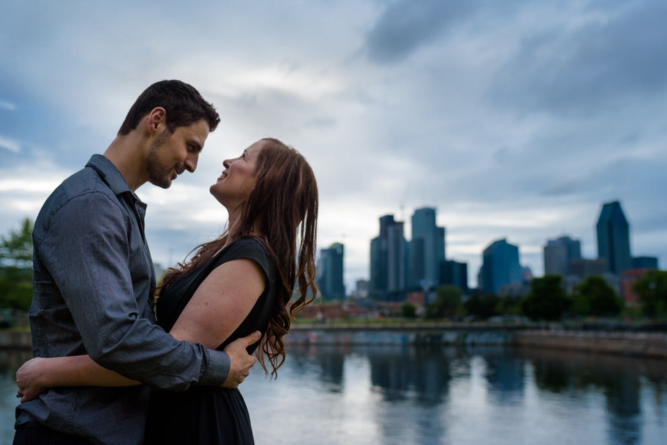 Engagement portrait along Lachine Canal with Montreal skyline behind them