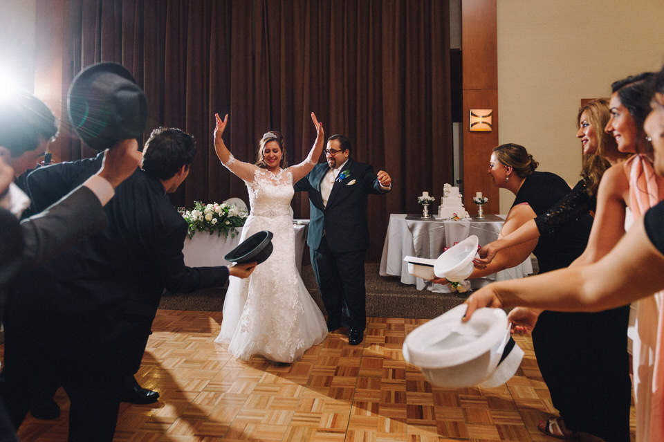 Guests dancing around bride and groom with hats
