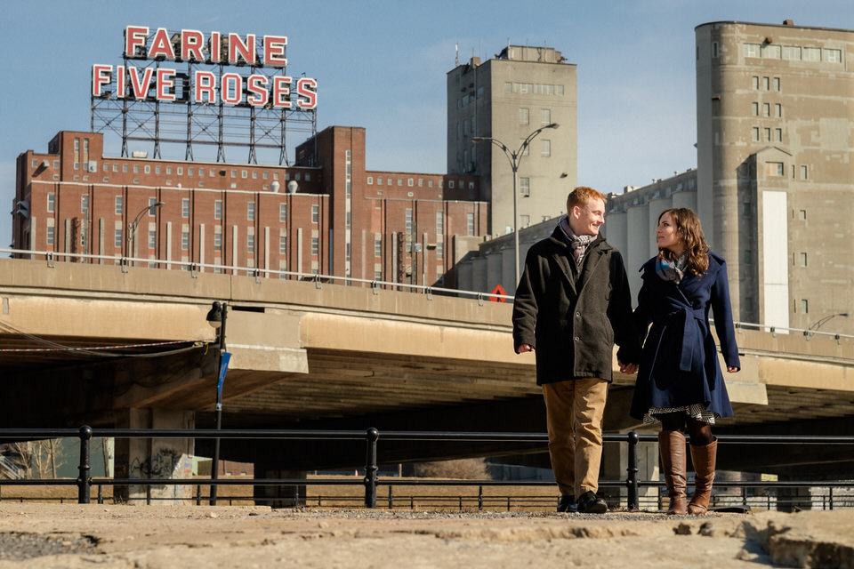 Engaged couple walking at Peel Bassins with Farine Five Roses sign behind them