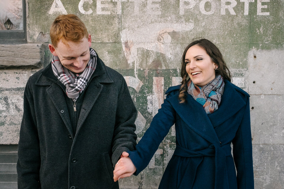 Couple holding hands in front of old wall