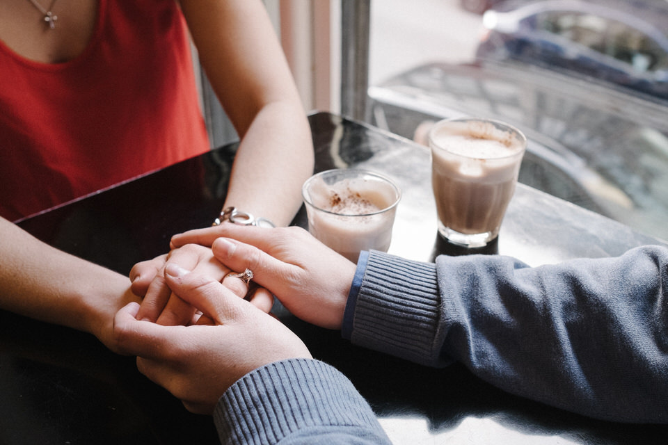 Engaged couple holding hands in coffeeshop