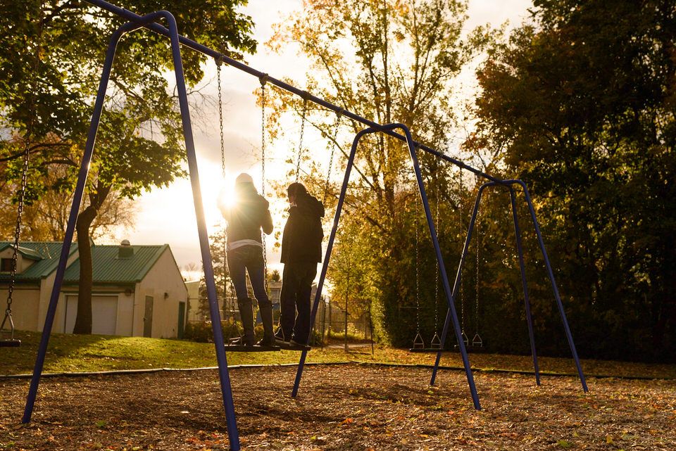 Couple swinging in a park on the sunset