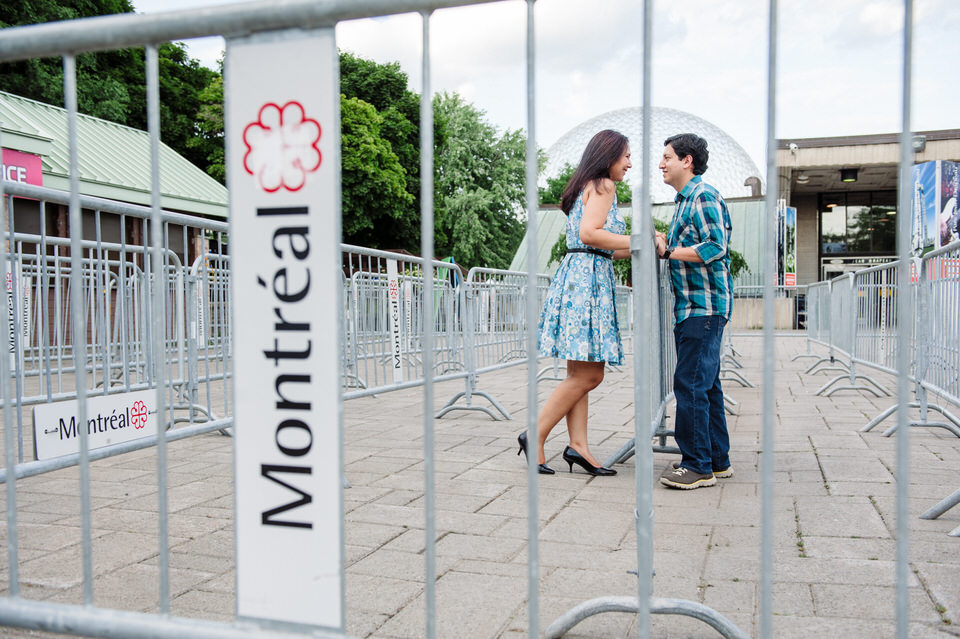 Engaged couple leaning on railing and framed by words "Montreal"