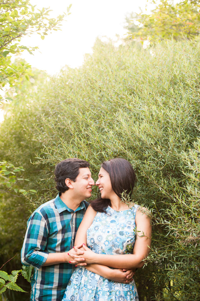 Engaged couple hugging in greenery at Jean-Drapeau Park