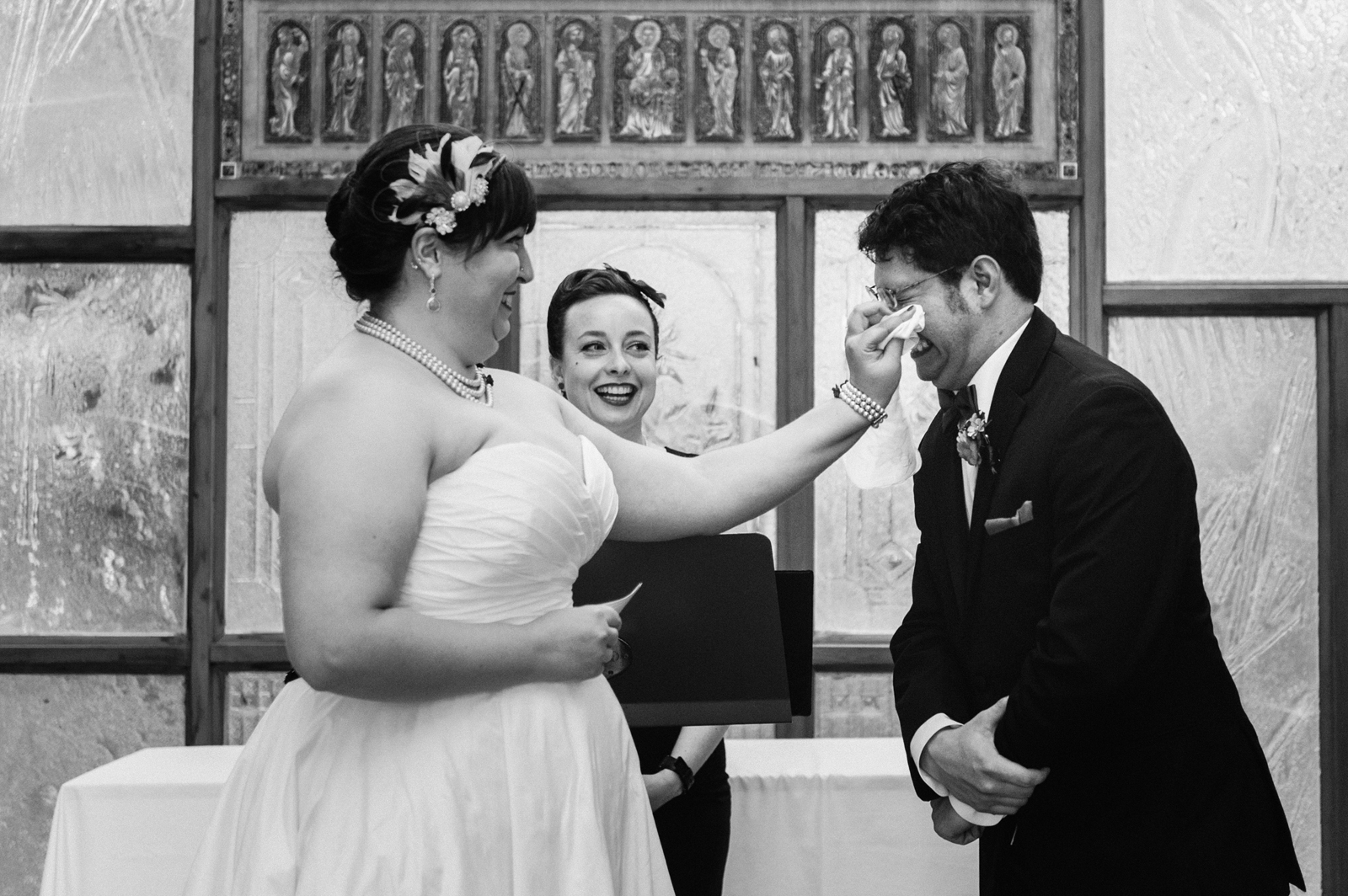 Bride wiping away groom's tears during wedding ceremony