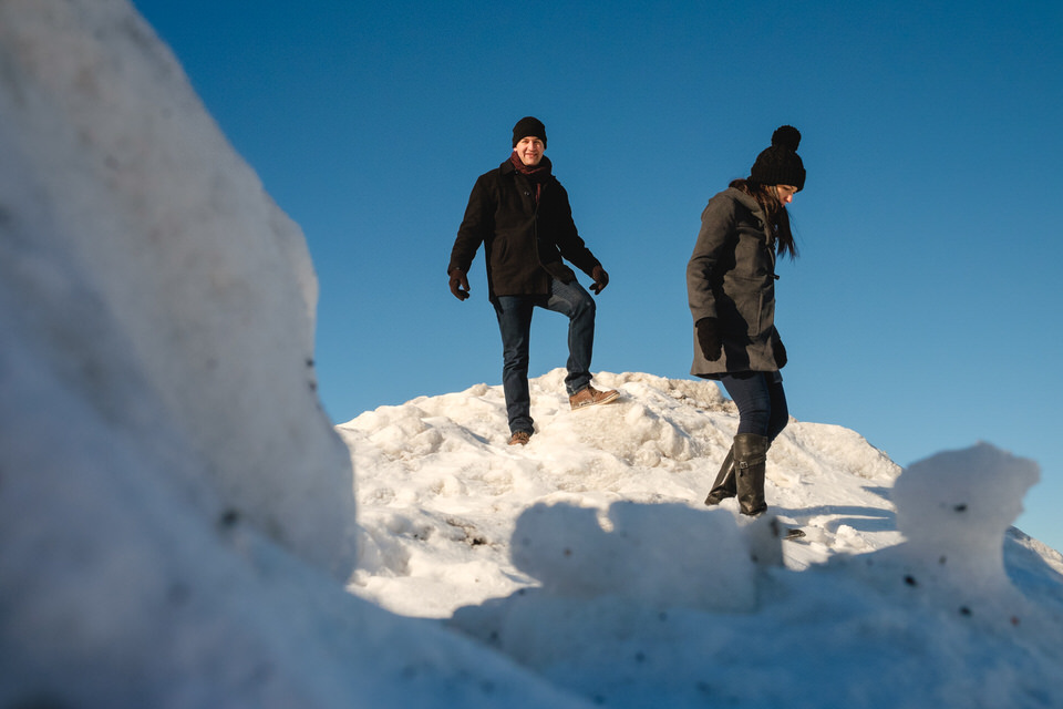 Newly engaged couple going down snowy mountain