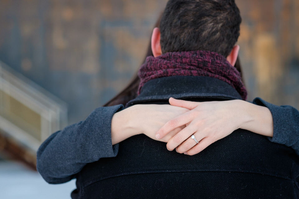 Close up image hands of fiancée around fiancé neck with her ring