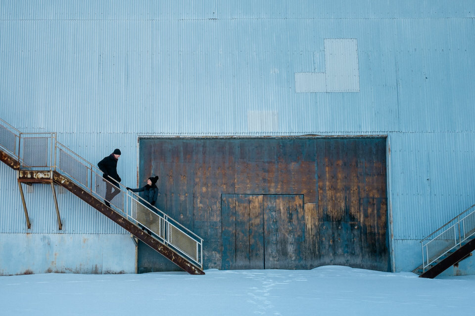 couple go down the stairs in front of a barn door