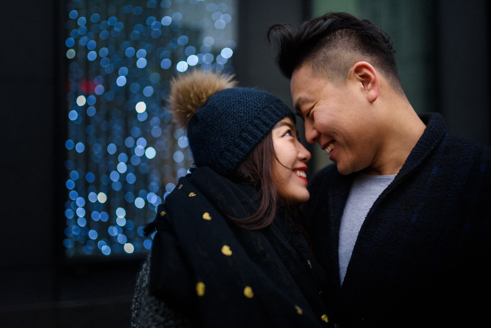 Couple smiling at each other with fairy lights behind them