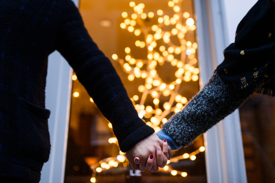 Couple holding hands in front of window with twinkle lights