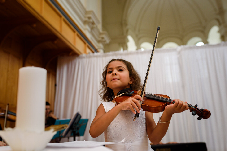 Bride's daughter playing violin at kid-friendly wedding ceremony