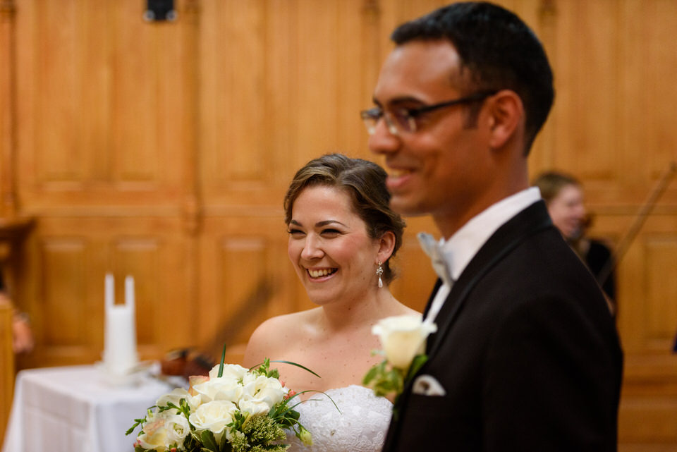 Smiling bride and groom look out at their wedding guests