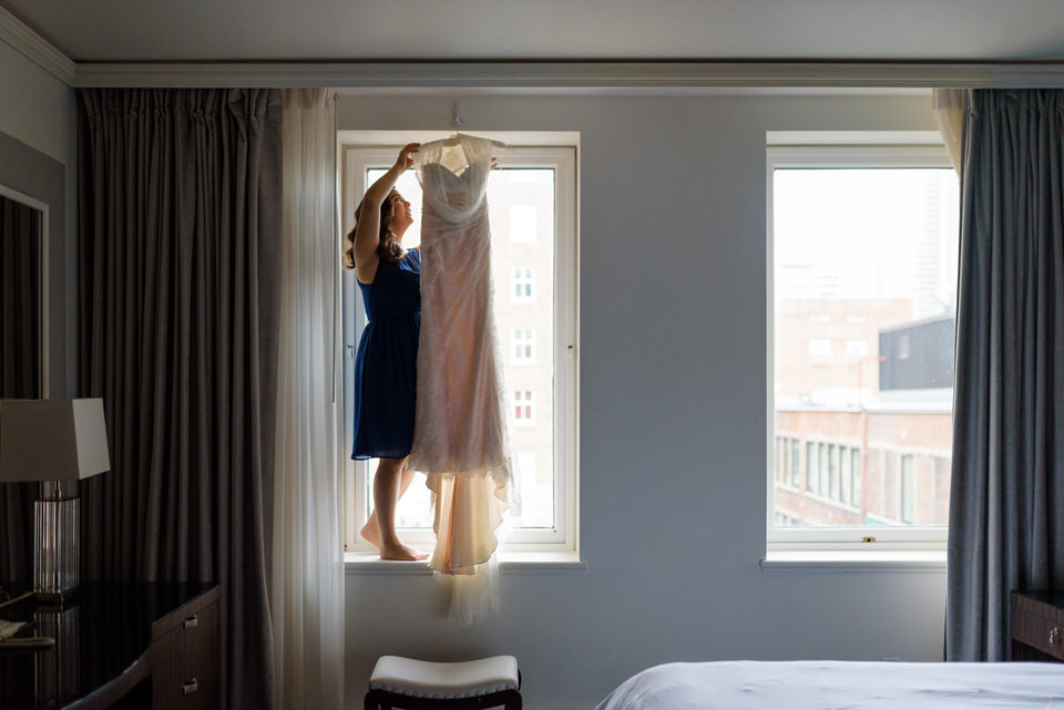 Bridesmaid hanging up wedding dress