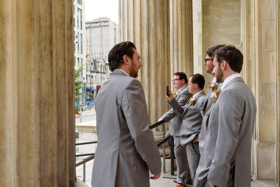 Groomsmen taking selfies in front of Montreal museum of fine arts 