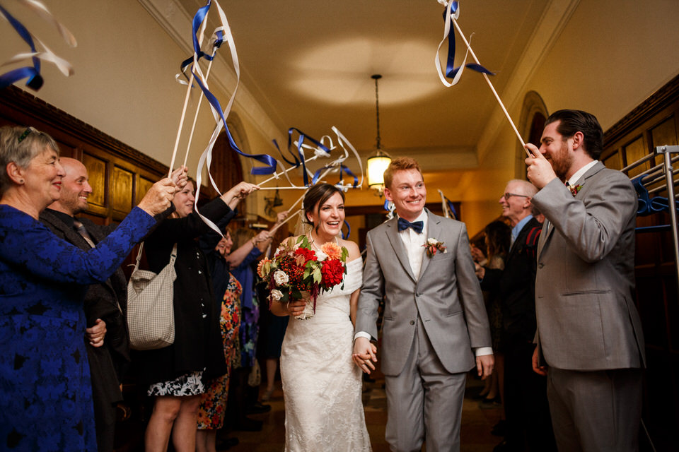 Family and friends waving ribbon stick at the married couple 