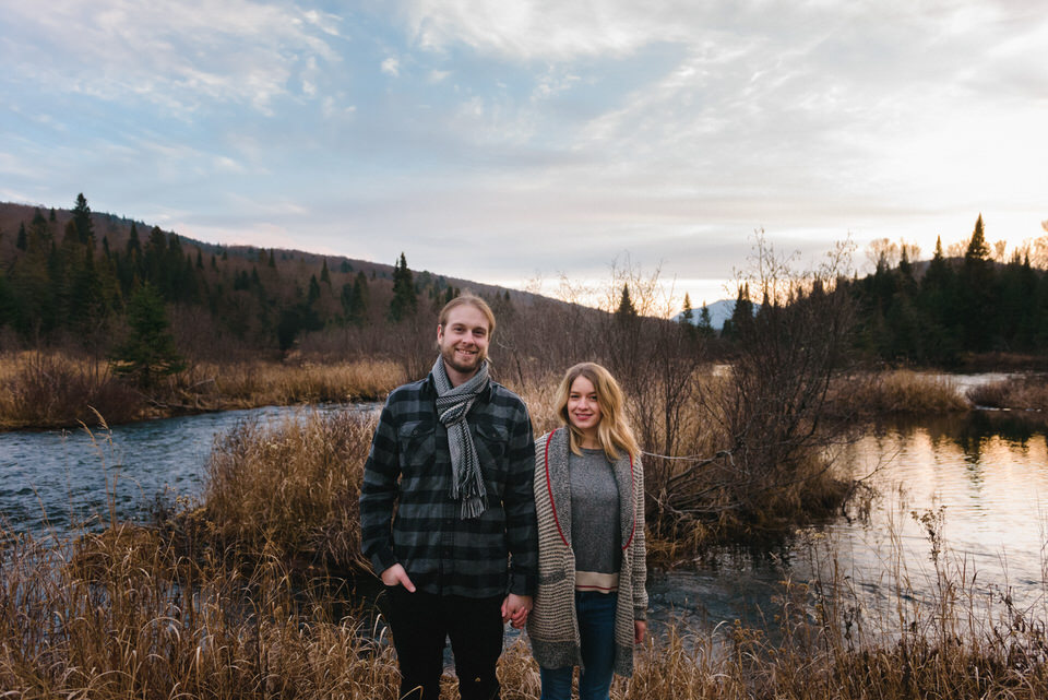 Engaged couple holding hands in front of wild landscape at Mont-Tremblant