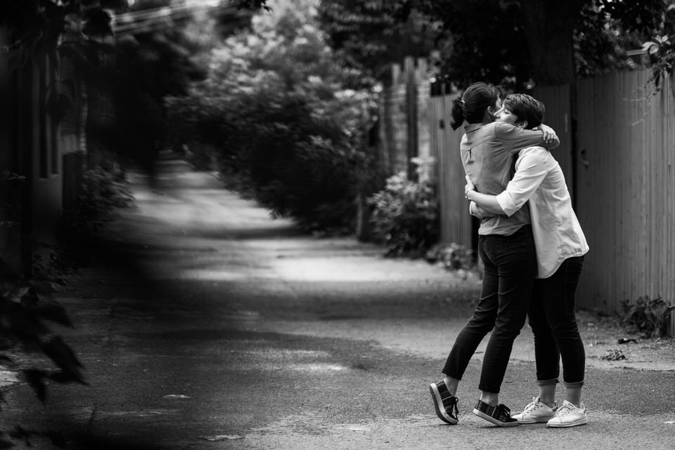 Same-sex couple hugging in Montreal's green alleyways