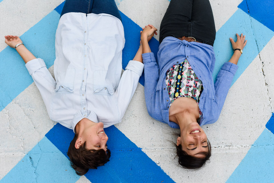 Lesbian couple lying down on graffiti and holding hands