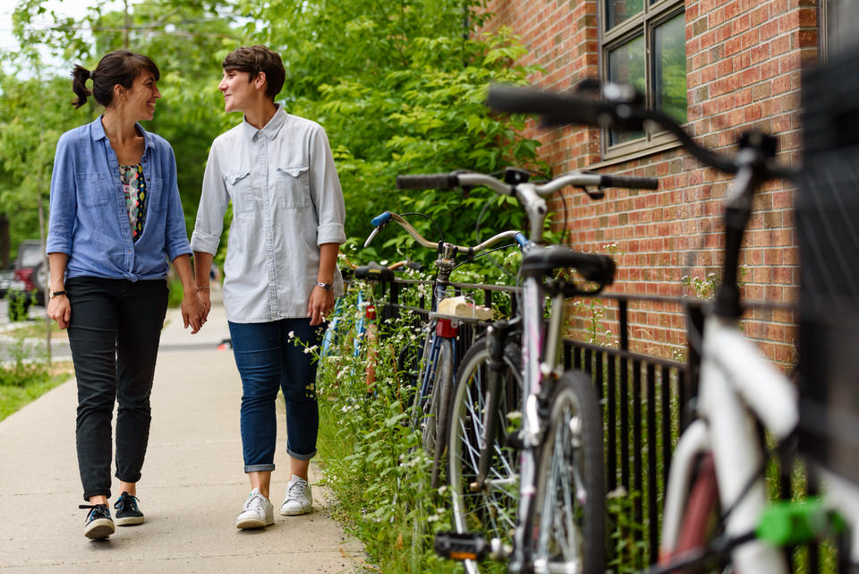 Lesbian couple walking along Montreal sidewalk near locked bikes