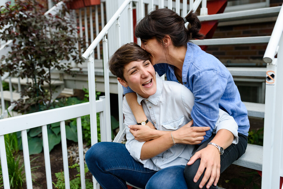 Lesbian couple laughing and hugging on stairs
