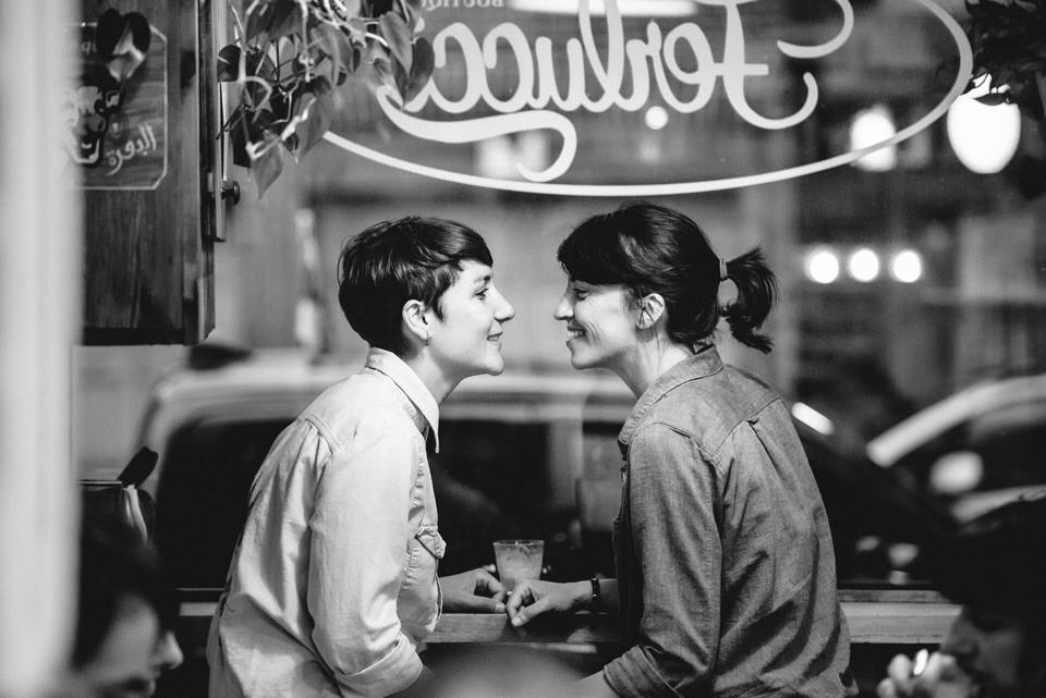 Engaged lesbian couple in romantic photo at Montreal cafe