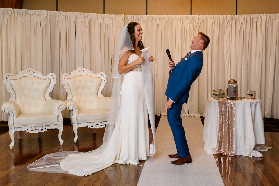 Groom laughing as bride unfurls long vows