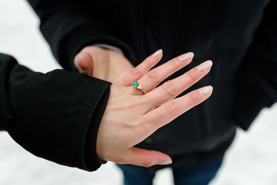 Close up of hands with emerald engagement ring